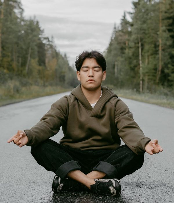 A person meditating peacefully in a natural setting like a forest.